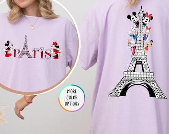 May include: Orchid-colored t-shirt featuring a front design with the word "Paris" and the Eiffel Tower, flanked by Mickey and Minnie Mouse. The back of the shirt displays a large Eiffel Tower design with Disney characters. The shirt is a comfortable, casual style.
