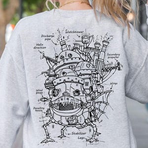 May include: A gray sweatshirt with a black line drawing of a flying machine on the back. The drawing is labeled with details such as 'Watchtower', 'Discharge pipe', 'Helix direction', 'Island gauge', 'Dwelling house', 'Secondary propeller', 'Stabilizer Legs'.