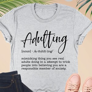 a t - shirt with the words, adulting and a pair of shoes