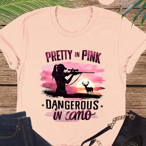 a pink shirt with a picture of a woman holding a gun
