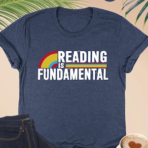 May include: A heather navy blue t-shirt with a rainbow arc and the text "Reading is Fundamental" in white.