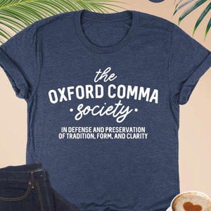 May include: A navy blue t-shirt with the text "the OXFORD COMMA Society." and the text "IN DEFENSE AND PRESERVATION OF TRADITION, FORM, AND CLARITY".