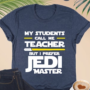 May include: A navy blue t-shirt with white text that reads "My Students Call Me Teacher But I Prefer Jedi Master". The text is in a Star Wars font style with yellow lightsaber accents.