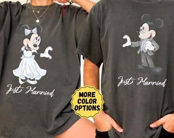 May include: A matching pair of t-shirts for a couple, with a vintage look. The woman's shirt features a cartoon image of Minnie Mouse in a white dress and the text "Just Married". The man's shirt features a cartoon image of Mickey Mouse in a tuxedo and the text "Just Married".
