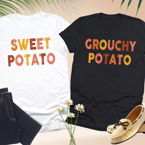 May include: A white t-shirt with the text SWEET POTATO in orange and yellow, and a black t-shirt with the text GROUCHY POTATO in orange and yellow. The text features a distressed, textured appearance on both short-sleeved crew neck garments.