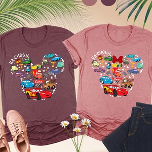 May include: Two heather t-shirts with a Mickey Mouse head design featuring the Cars characters. The left shirt is heather maroon and the right shirt is heather mauve. The design includes the text "KA-CHOW!" and "Cars".