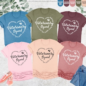 May include: Six different color t-shirts with the text "compassionate, caring, dedicated" in a heart shape around the words "Veterinary Squad" in white text.