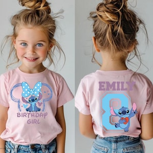 May include: Pink short-sleeved t-shirt featuring a cartoon character with a blue bow and the text "BIRTHDAY GIRL". The back of the shirt has the name "EMILY" and the number "8" in blue. The shirt is worn by a young girl.
