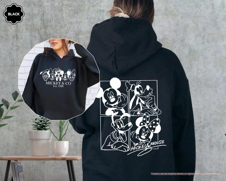 May include: Black hoodie featuring a white graphic of Mickey Mouse and friends. The front of the hoodie displays "MICKEY & CO Est. 1928". The back has a four-panel design with Mickey, Goofy, Donald, and Minnie Mouse. A classic Disney-themed apparel item.