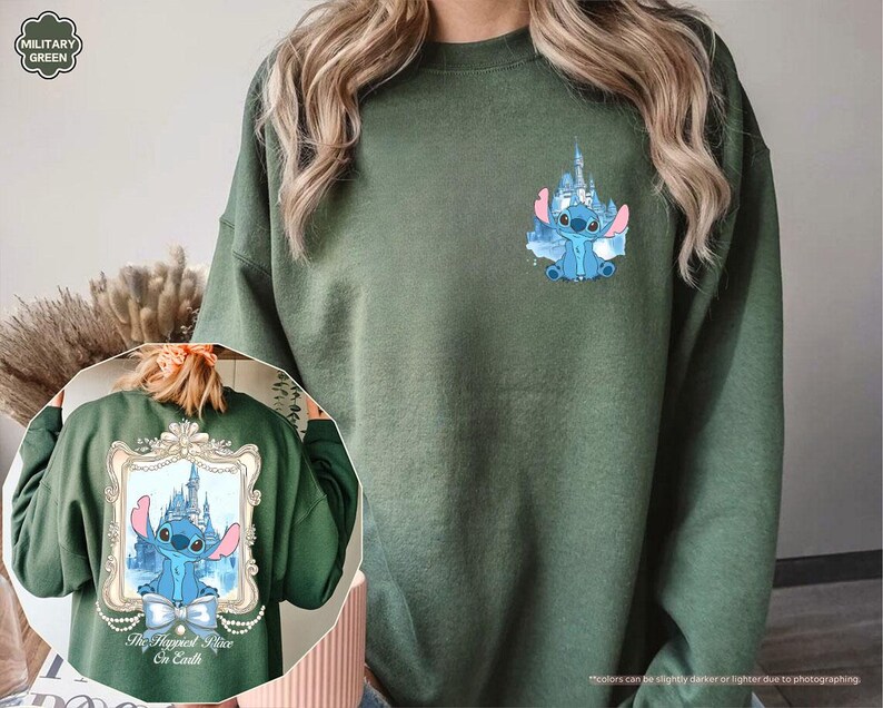 May include: Military green sweatshirt featuring a blue cartoon character with a castle graphic. The design is repeated on the back within a decorative frame, with the text "The Happiest Place on Earth". The sweatshirt is a solid color with a crew neck.