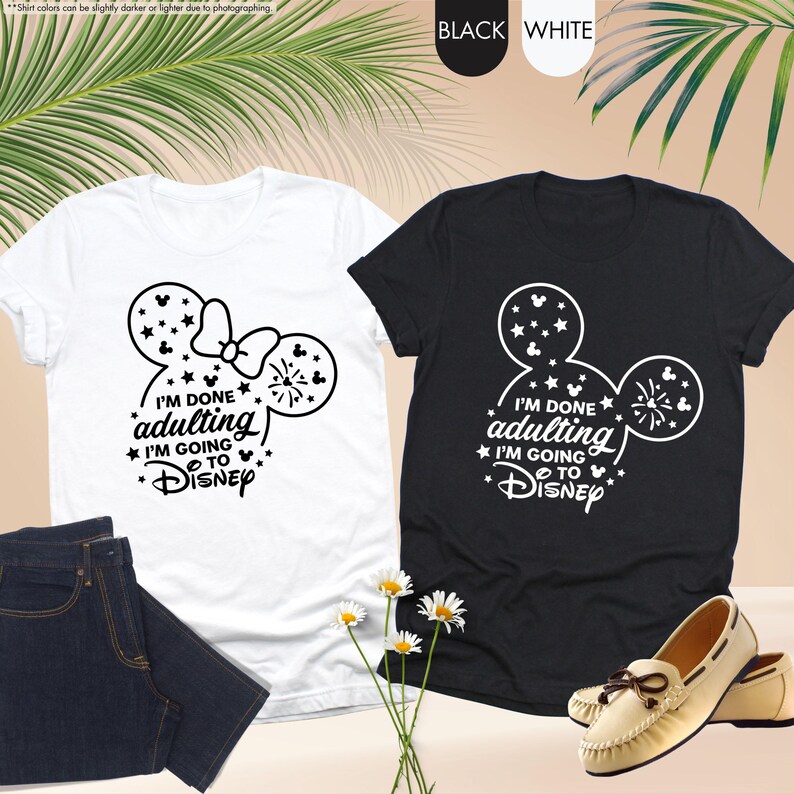 May include: Two t-shirts with a black and white Mickey Mouse design. The white t-shirt has a bow on the Mickey Mouse ears. The black t-shirt has a firework design. Both shirts have the text "I'm done adulting I'm going to Disney".