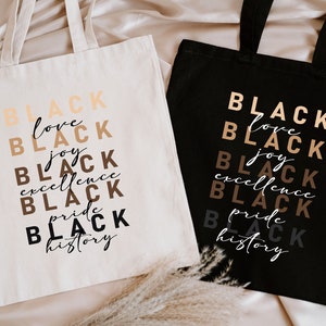 two black and white shopping bags sitting on a bed