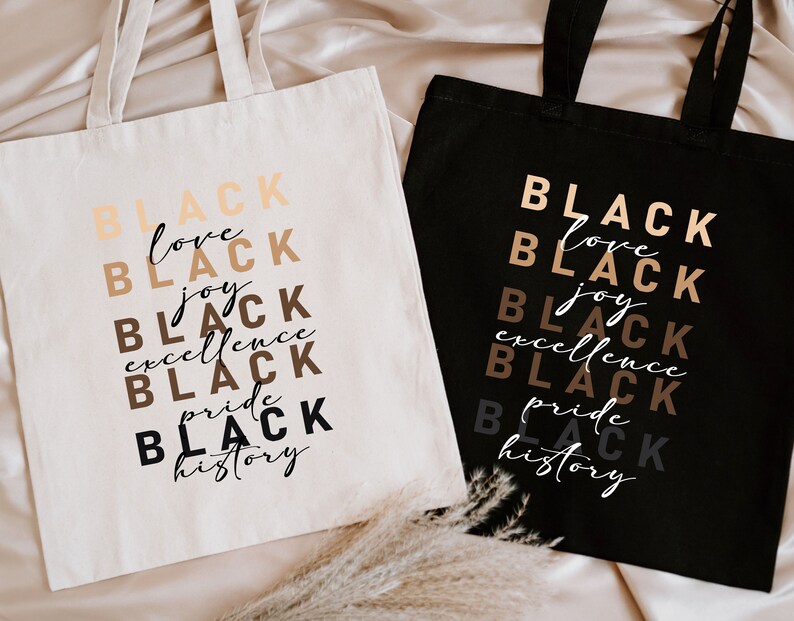 two black and white shopping bags sitting on a bed