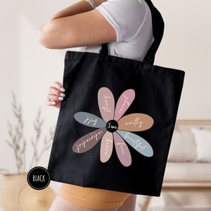 a woman holding a black bag with a flower on it