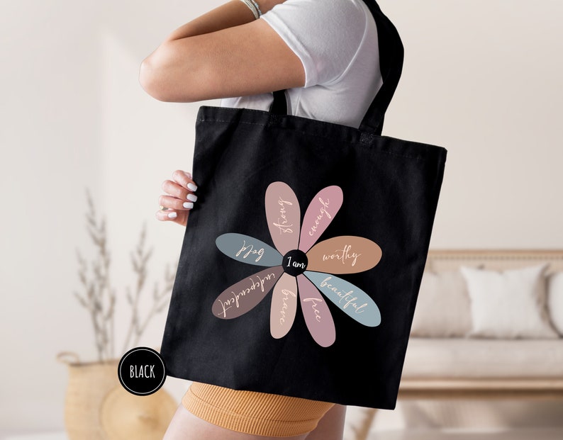 a woman holding a black bag with a flower on it