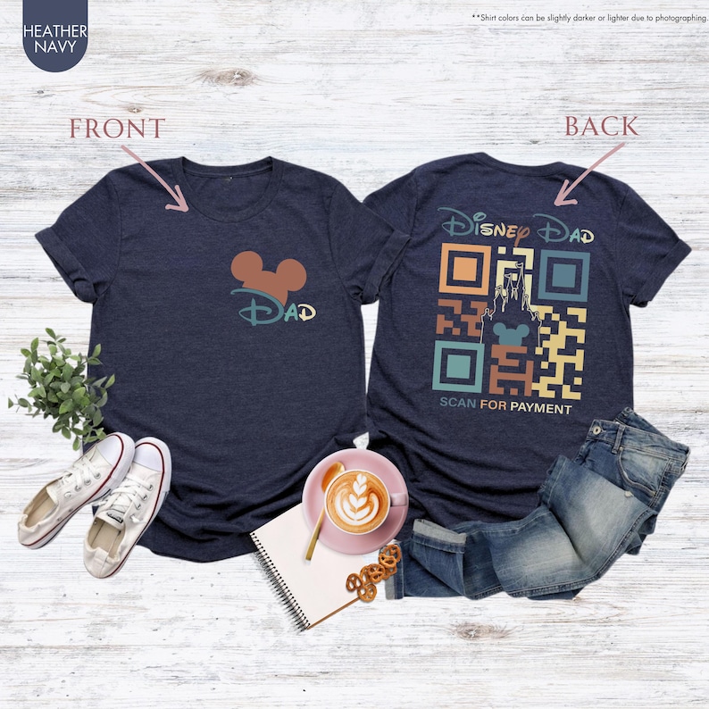 May include: A heather navy blue t-shirt with a Mickey Mouse head and the word "DAD" on the front. The back of the shirt has a retro-style QR code with a Disney castle and Mickey Mouse head, and the text "Disney DAD" and "SCAN FOR PAYMENT".