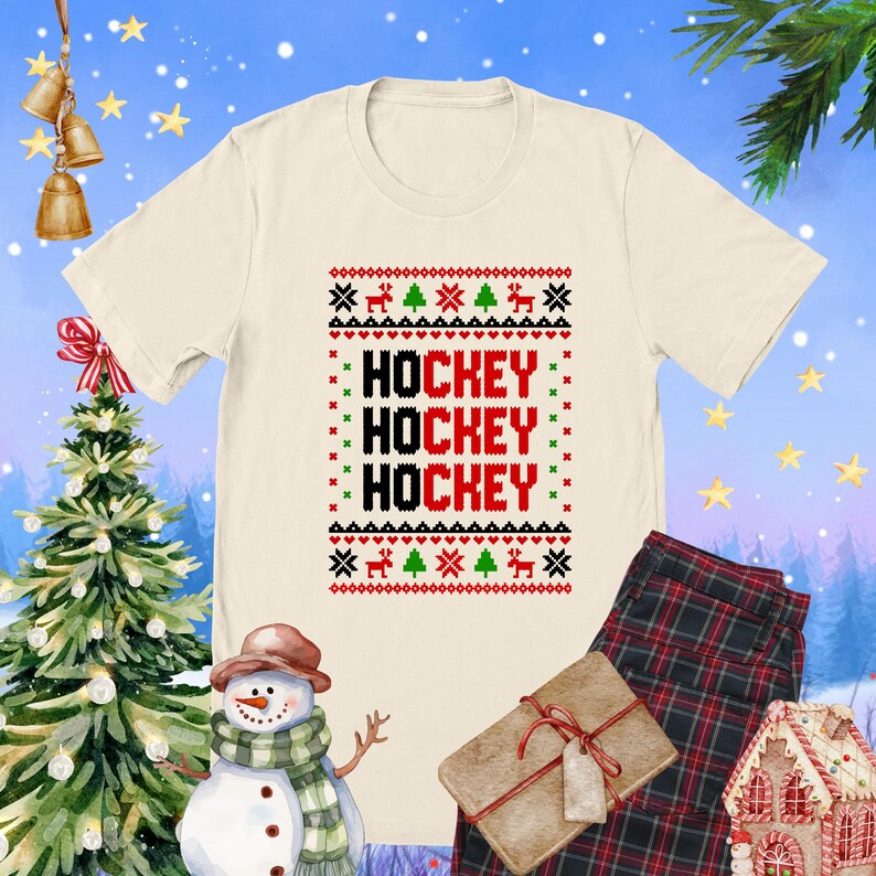 May include: A white t-shirt with a red, green, and black Christmas sweater design. The design features the word "HOCKEY" repeated three times.