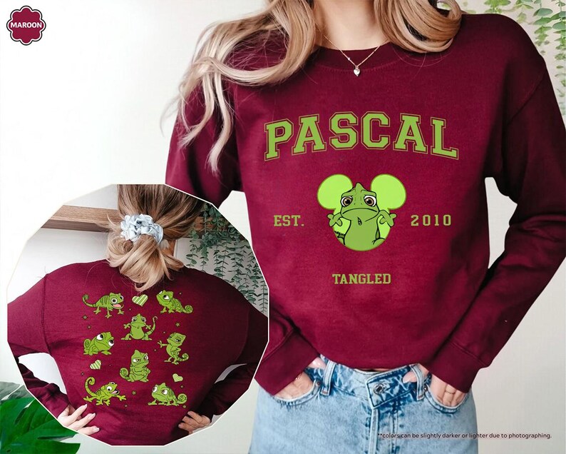 Op de afbeelding: Bordeaux sweatshirt met het woord "PASCAL" in groene blokletters, een groene cartoonkameleon en de tekst "EST. 2010 TANGLED." De achterkant van de sweatshirt heeft groene kameleongraphics. De sweatshirt wordt gedragen met een blauwe spijkerbroek.