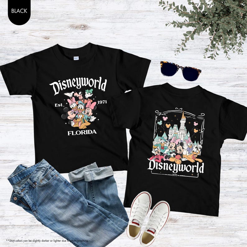 May include: Two black t-shirts with Disneyworld graphics, one featuring characters and the text "Est. 1971 Florida," and the other with a castle and characters. The shirts are paired with blue jeans and white sneakers.