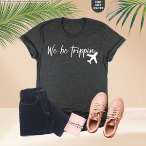 a t - shirt that says we are tripping next to a pair of jeans