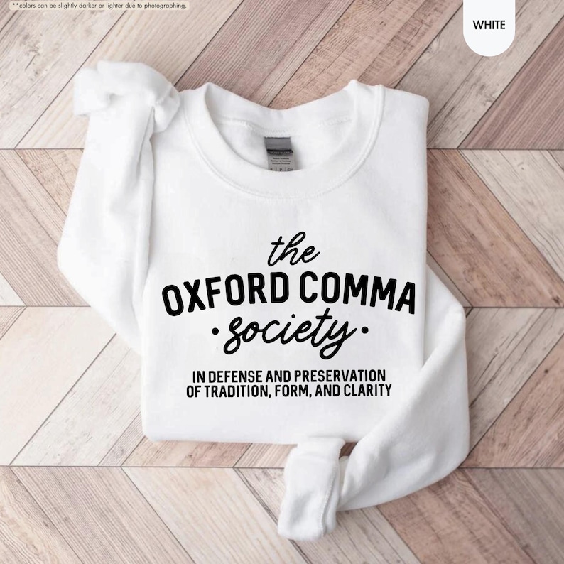 Op de afbeelding: Wit sweatshirt met zwarte tekst die "the OXFORD COMMA society. IN DEFENSE AND PRESERVATION OF TRADITION, FORM, AND CLARITY" luidt.