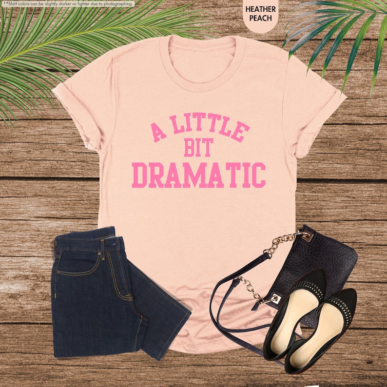 a t - shirt that says a little bit dramatic next to a pair of jeans