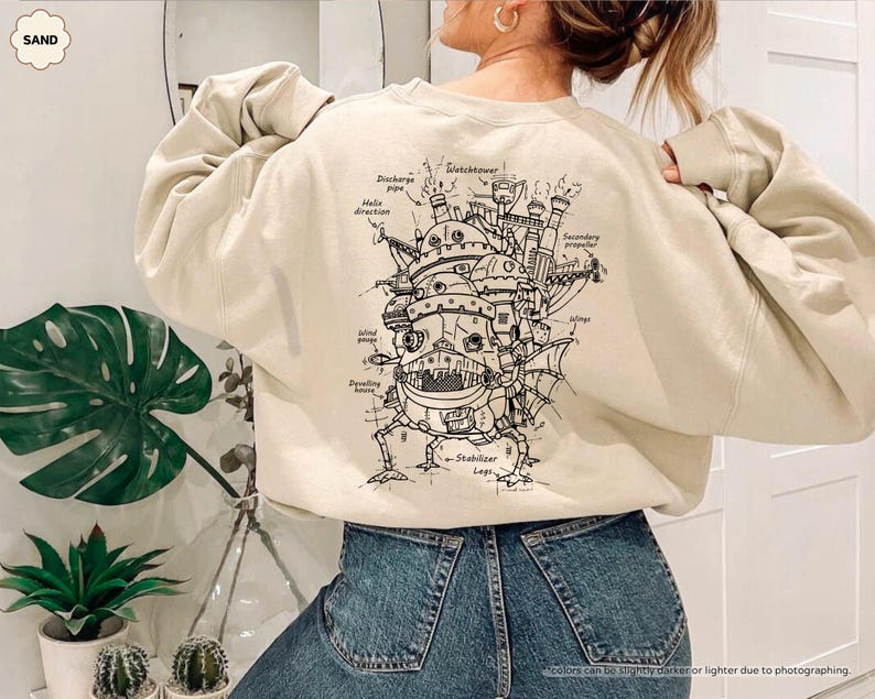 May include: A beige sweatshirt with a black and white illustration of a flying machine on the back. The illustration includes labels for different parts of the machine, such as "Watchtower", "Discharge pipe", and "Stabilizer Legs".