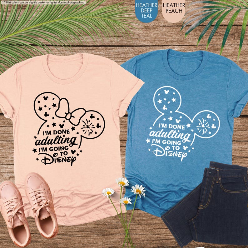 May include: Two t-shirts with a Mickey Mouse ear design. The pink shirt says "I'm done adulting I'm going to Disney" in black text. The blue shirt says "I'm done adulting I'm going to Disney" in white text.
