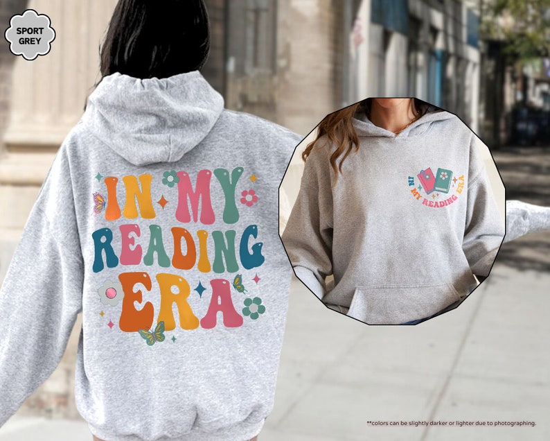 a woman wearing a gray hoodie with the words in my reading era on it