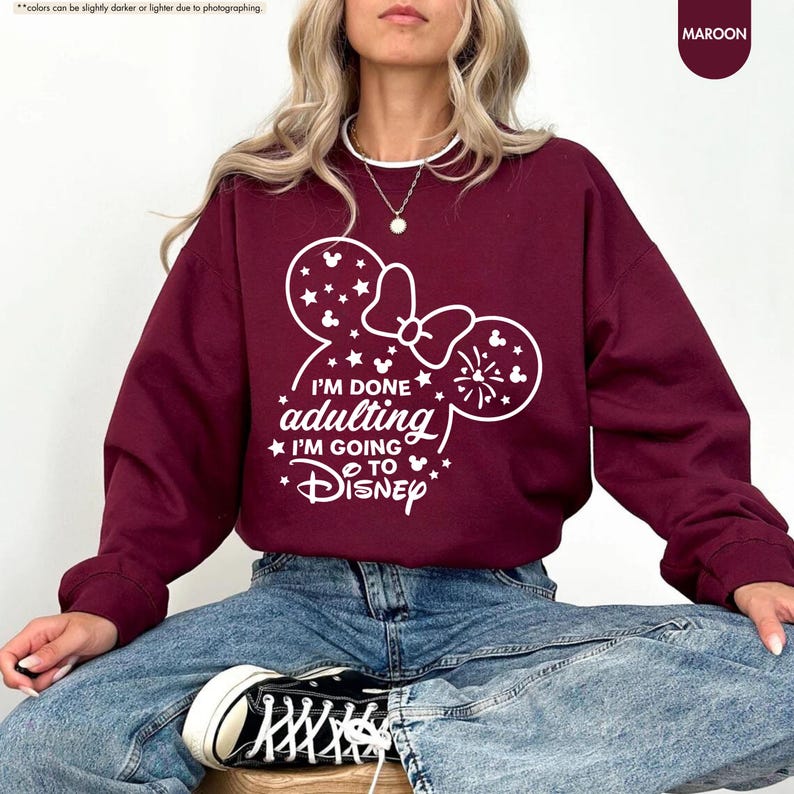 May include: A maroon sweatshirt with a white graphic of a Mickey Mouse ear silhouette with a bow and the text "I'm done adulting I'm going to Disney".