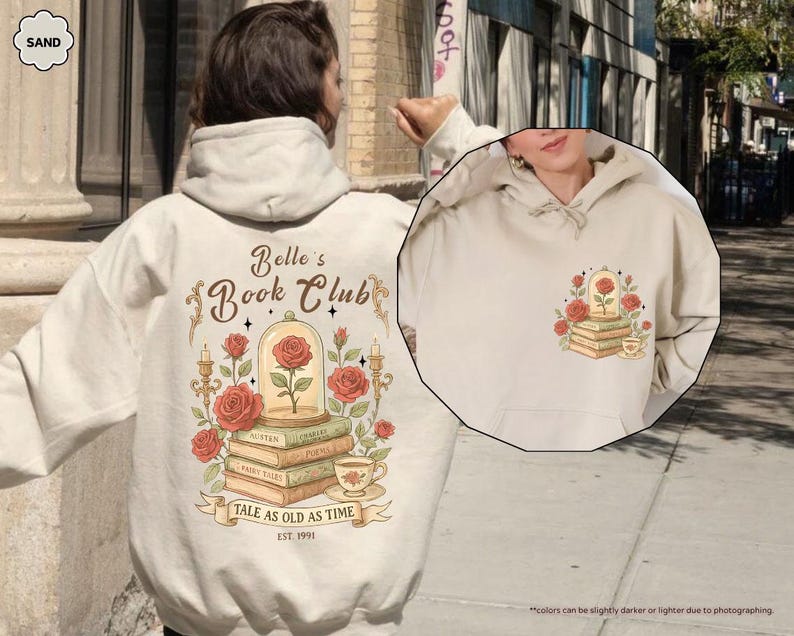 Puede incluir: Sudadera con capucha color arena con un gr&aacute;fico de una rosa en una c&uacute;pula de cristal sobre libros, con el texto "Belle's Book Club" y "Tale as Old as Time". El dise&ntilde;o incluye rosas, velas y una taza de t&eacute;. La sudadera tiene un bolsillo delantero y una capucha.