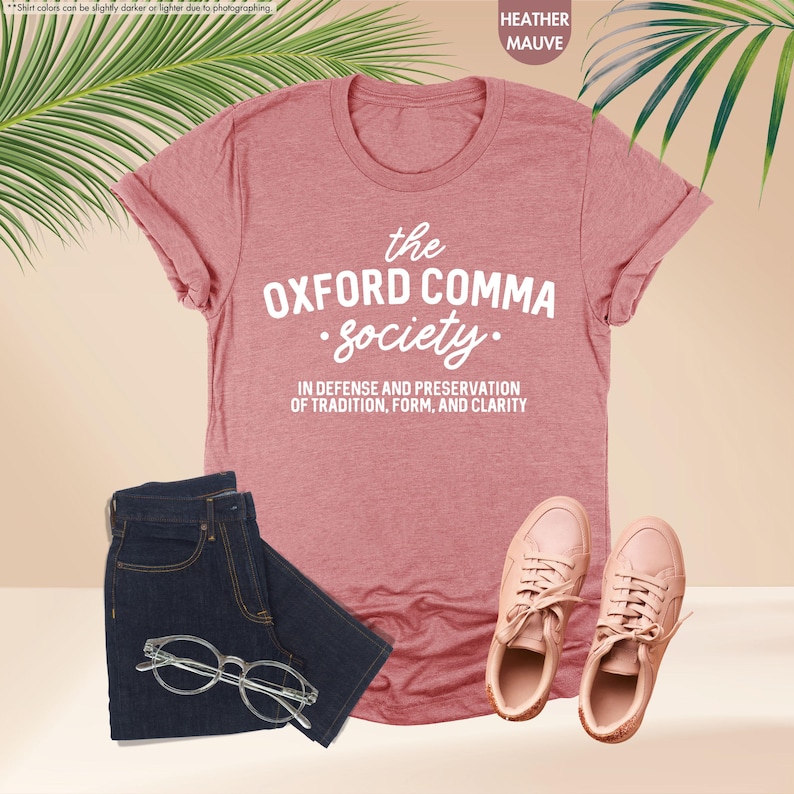 Op de afbeelding: Heather mauve t-shirt met de tekst "the OXFORD COMMA Society." en de tekst "IN DEFENSE AND PRESERVATION OF TRADITION, FORM, AND CLARITY."