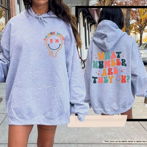 a woman in a blue hoodie is walking down the street