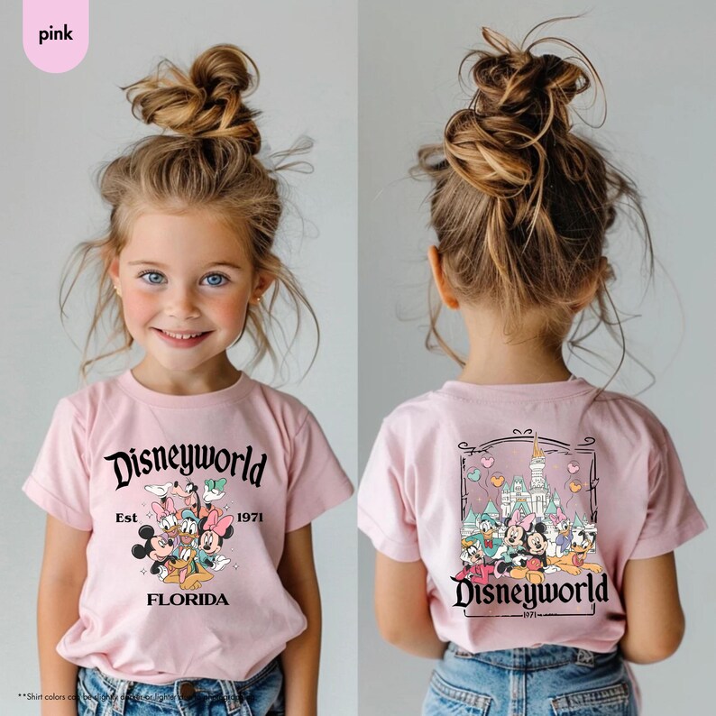 May include: Pink t-shirt with a Disneyworld graphic. The front features Mickey, Minnie, Donald, Daisy, and Goofy. The back shows a castle and more characters. The text reads "Disneyworld Est 1971 Florida".