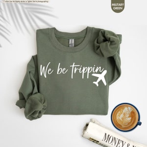 a t - shirt that says we be tripping next to a cup of coffee