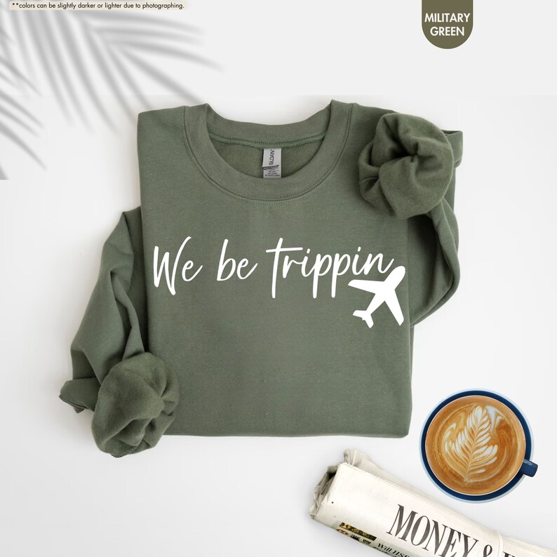 a t - shirt that says we be tripping next to a cup of coffee