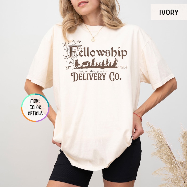 May include: A cream colored t-shirt with a brown graphic of the Fellowship of the Ring walking with the text "Fellowship" above and "EST 1954 fast, reliable, precious DELIVERY CO." below.