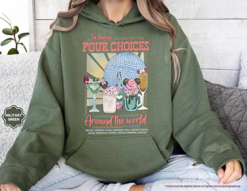 Pu&ograve; includere: Felpa con cappuccio verde militare con una grafica che dice "I'm Making Pour Choices Around the World". La grafica presenta cocktail colorati e una sfera blu. La felpa con cappuccio include un elenco di paesi.