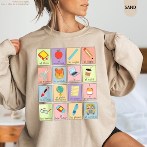 a woman wearing a sweatshirt with a picture of school supplies on it