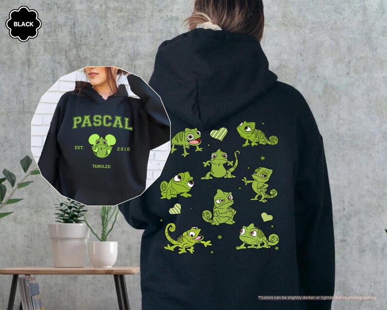 Op de afbeelding: Zwarte hoodie met een groen Pascal-ontwerp uit de film Rapunzel. De voorkant heeft het woord "PASCAL" en een Pascal-afbeelding. De achterkant toont meerdere groene Pascal-illustraties en harten.
