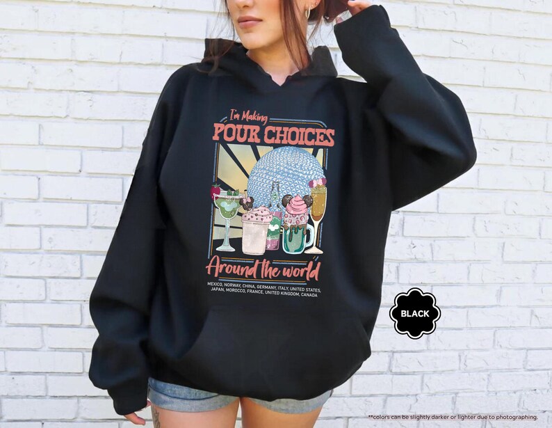 Pu&ograve; includere: Felpa con cappuccio nera con una grafica che recita "I'm Making POUR CHOICES Around the world". La grafica presenta illustrazioni di cocktail e un globo. La felpa con cappuccio &egrave; nera con cappuccio con coulisse e tasca frontale.