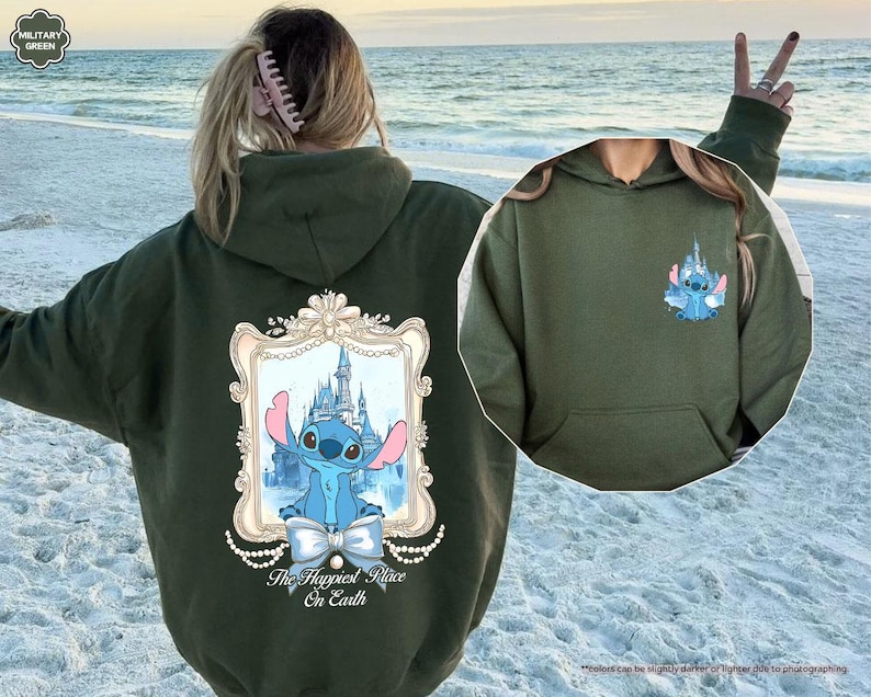 May include: Olive green hoodie featuring a cartoon image of Stitch in front of a castle, framed with a decorative border and the text "The Happiest Place On Earth." A smaller Stitch graphic is on the chest. The hoodie has a front pocket.