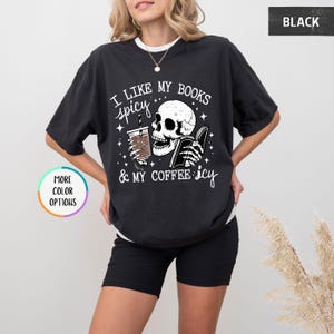 May include: Black graphic t-shirt with the text "I like my books spicy & my coffee icy." The design features a skull holding a book and a coffee cup. The shirt has a relaxed fit.