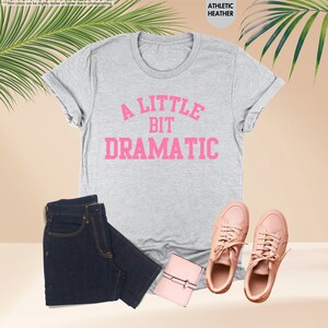 a t - shirt that says a little bit dramatic next to a pair of jeans
