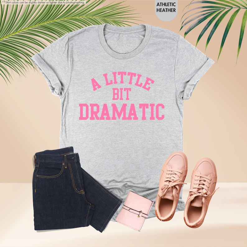 a t - shirt that says a little bit dramatic next to a pair of jeans