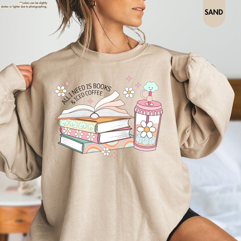 a woman wearing a sweatshirt with a book and a drink on it