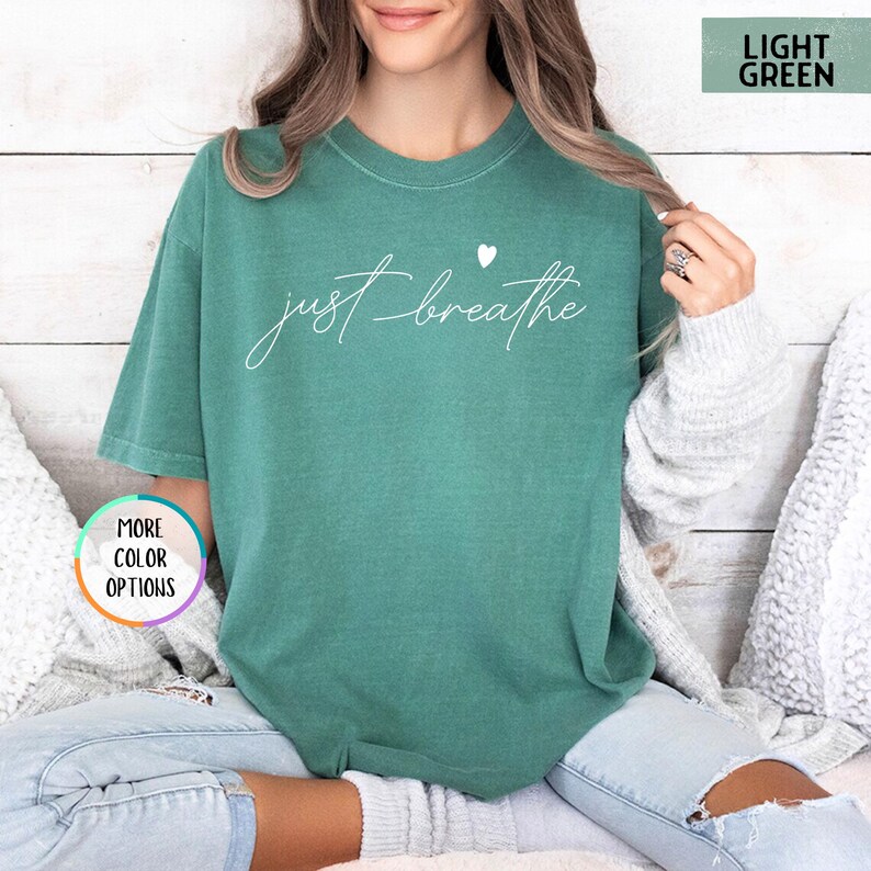 May include: A light green t-shirt with the text "just breathe" in white lettering and a small white heart above the text.