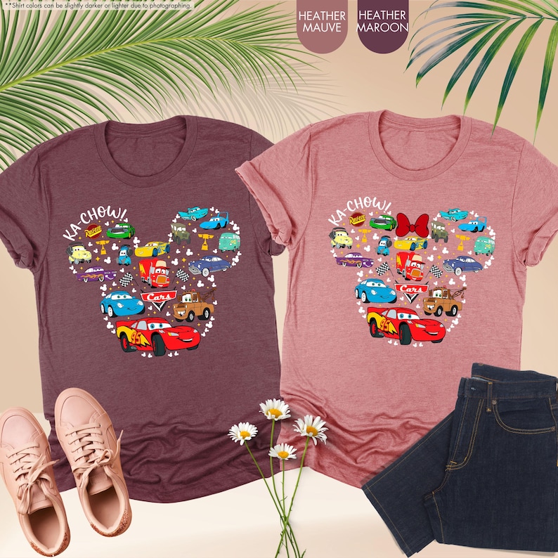 May include: Two heather t-shirts with a Mickey Mouse head design featuring the Cars characters. The left shirt is heather maroon and the right shirt is heather mauve. The design includes the text "KA-CHOW!" and "Cars".