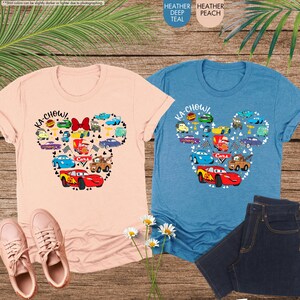 May include: Two t-shirts featuring a Mickey Mouse silhouette made up of Cars characters. The text "Ka-Chow!" is on the shirts. One shirt is peach and the other is teal.