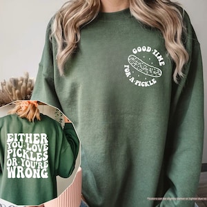 a woman wearing a green sweatshirt with a picture of a pizza on it